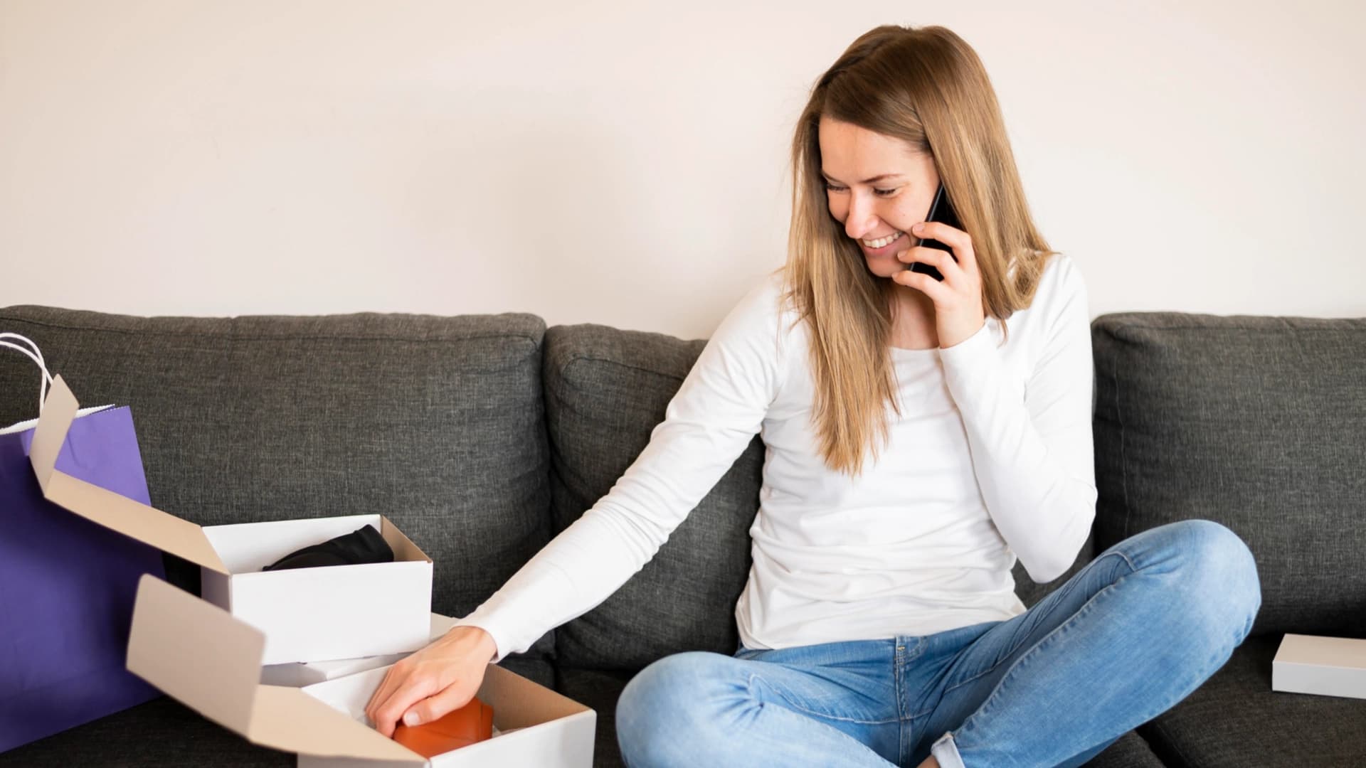 Vrouw die op de bank zit met haar online gekochte producten.