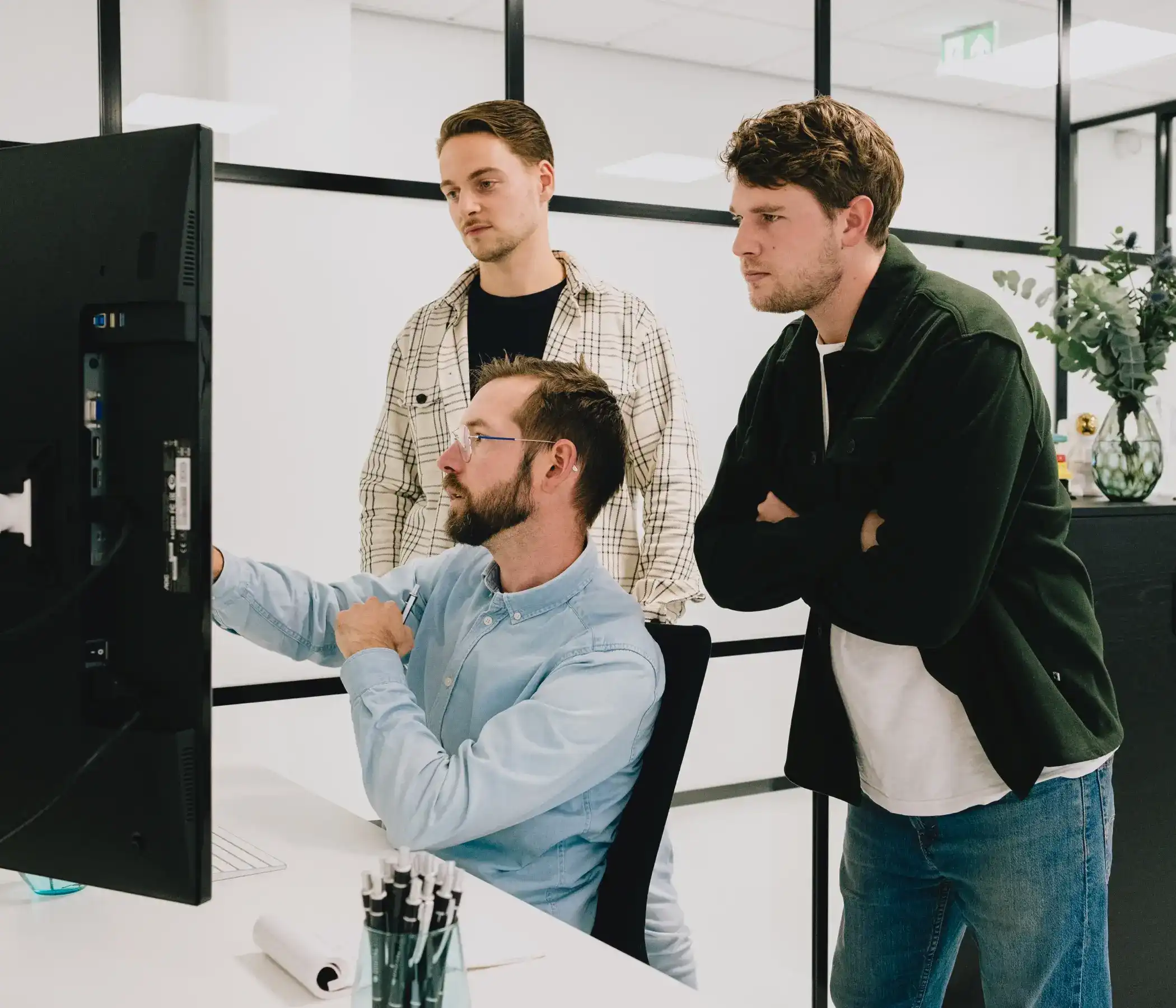 Sam en Leendert staan bij Joost die hen in uitleg geeft over een project