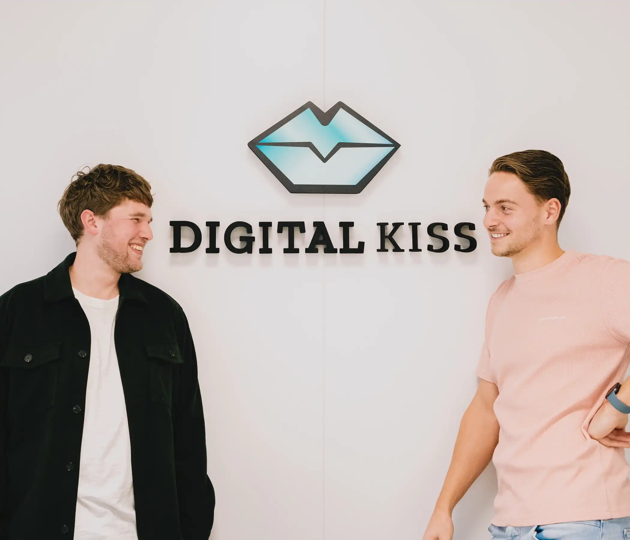 Sam en Leendert poseren bij het logo van Digital Kiss
