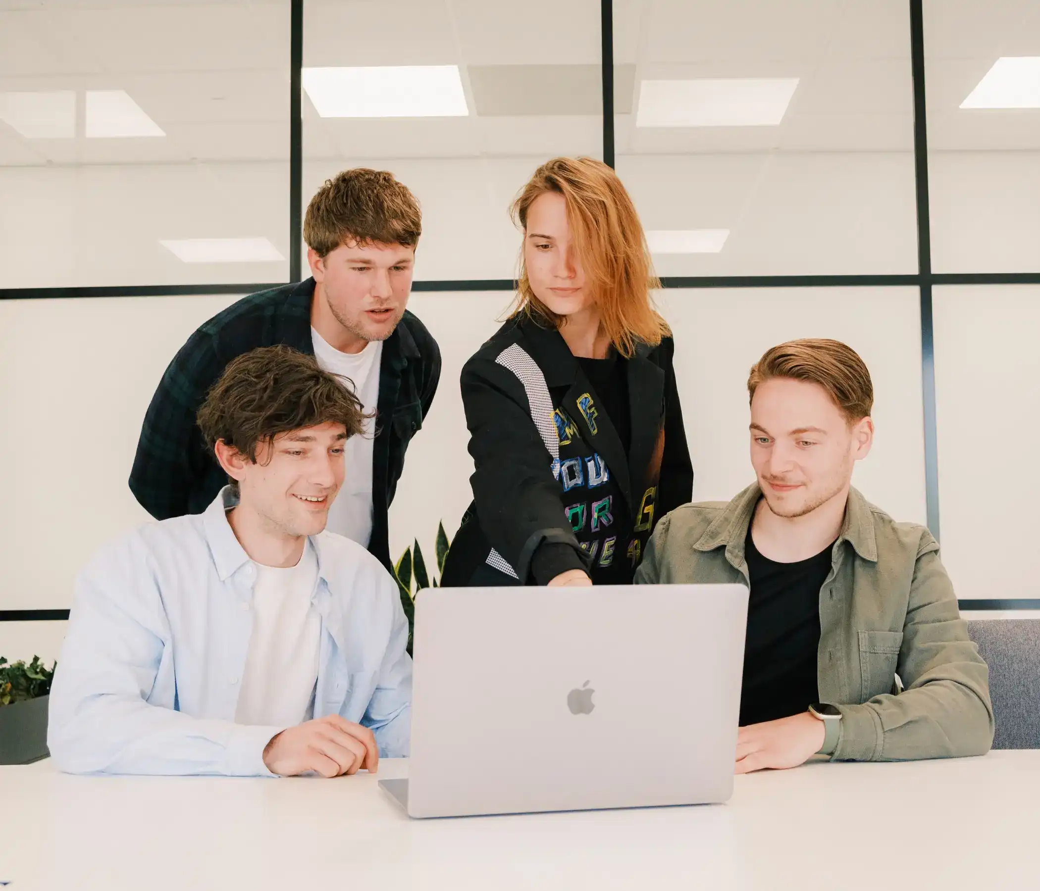 De medewerkers van Digital Kiss zitten en staan in overleg rond een laptop